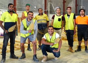 group of adult men in work wear at brick laying training course smiling at camera