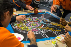 group of people painting aboriginal art