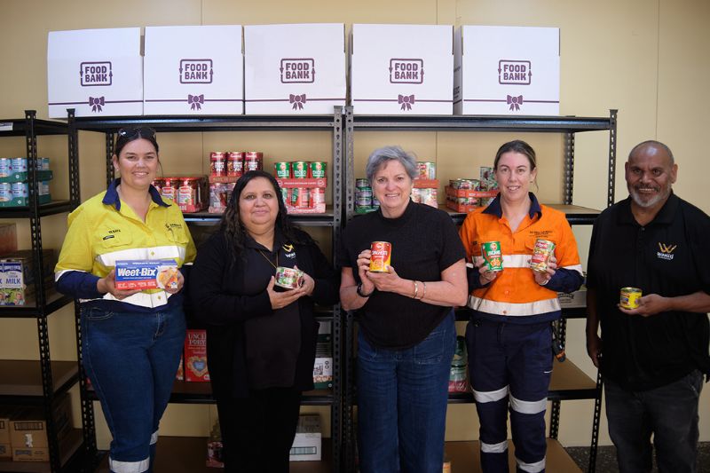 five people standing in front of shelving with food